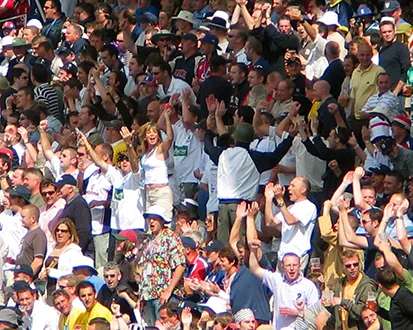 A photo of a large group of people all sitting on stadium benches