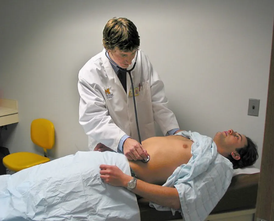A color photograph shows a doctor using an stethoscope to check the abdomen of a patient.