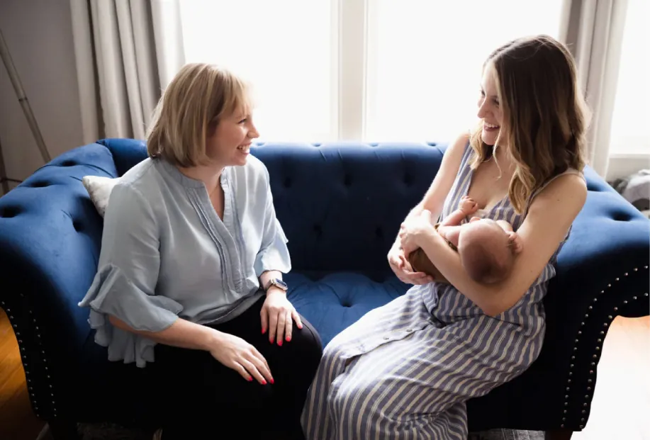 A practitioner happily regards a person holding a newborn.