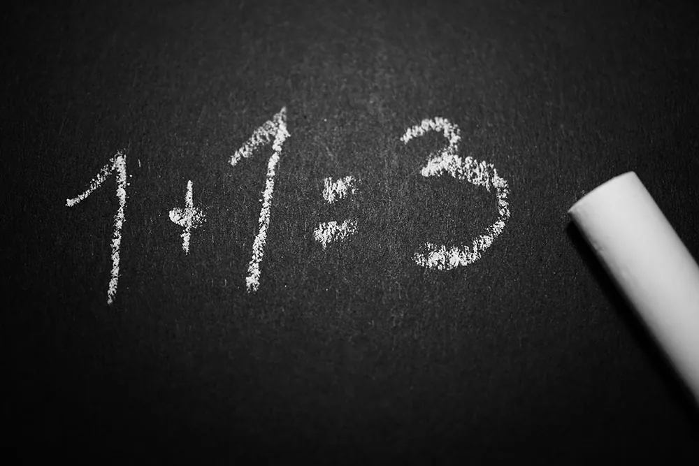 A blackboard shows 1 + 1 = 3 written in white chalk.