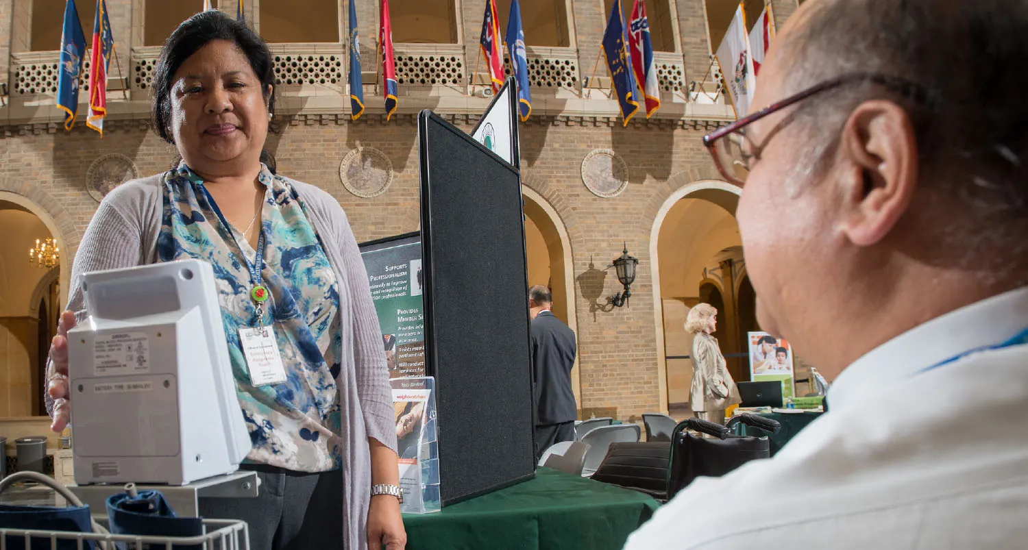 A color photograph shows a nurse wearing lanyard operating computer equipment.