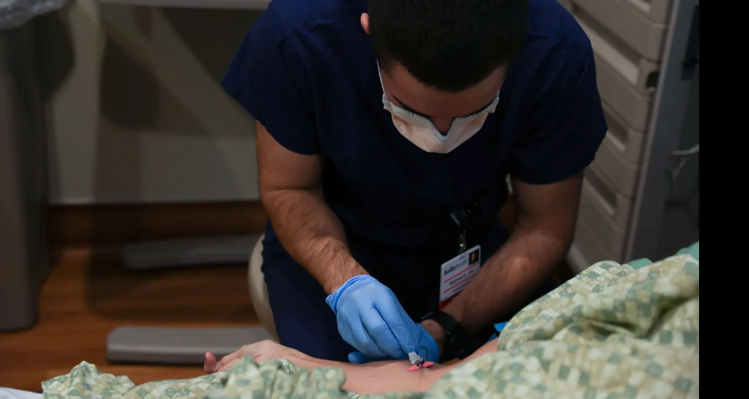 A nurse collecting blood from a patient in bed.