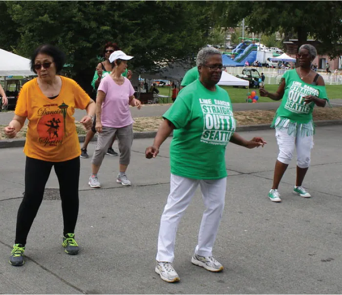 Four older women dance outside.