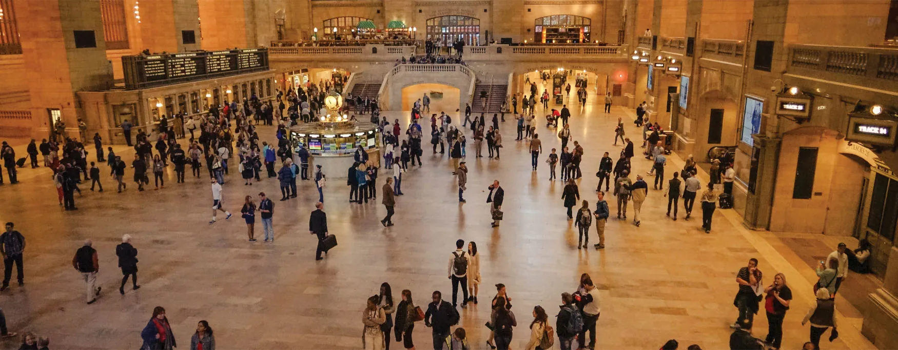 Photo of large hall in Grand Central Station filled with people walking around.
