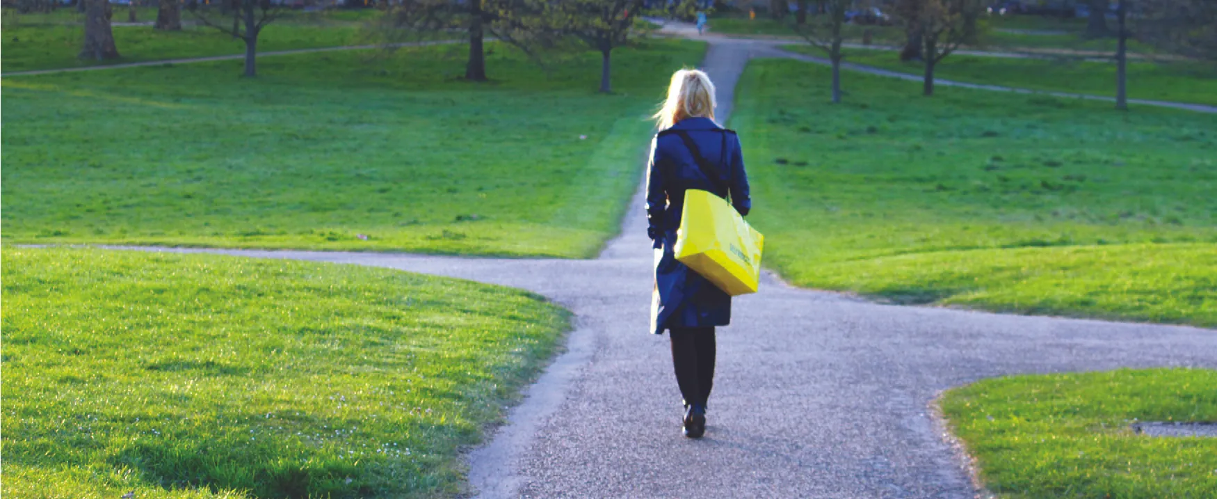 A photograph of a woman walking on a path that branches off in different directions.