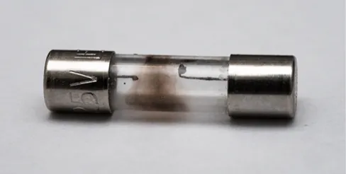 Na zdjęciu przepalony bezpiecznik z przepalonym drutem w środku. 