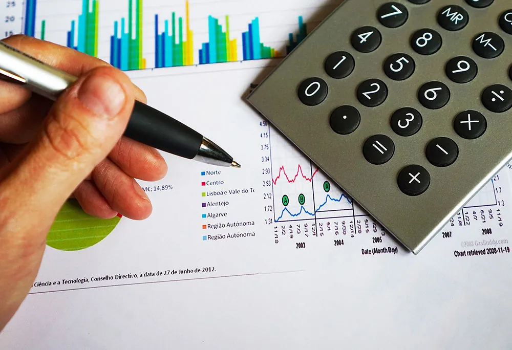 A photo shows a person holding a black and gray pen while reviewing business metrics.