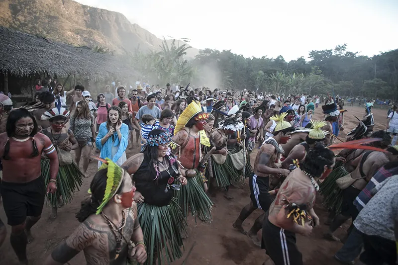 A multiethinc group of people from the Amazon at an outdoor celebration. All are wearing traditional dress.