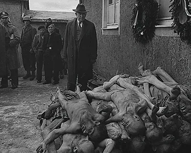 A U.S. senator, congressional committee member, and several other officials examine a massive heap of emaciated corpses at the Buchenwald concentration camp.