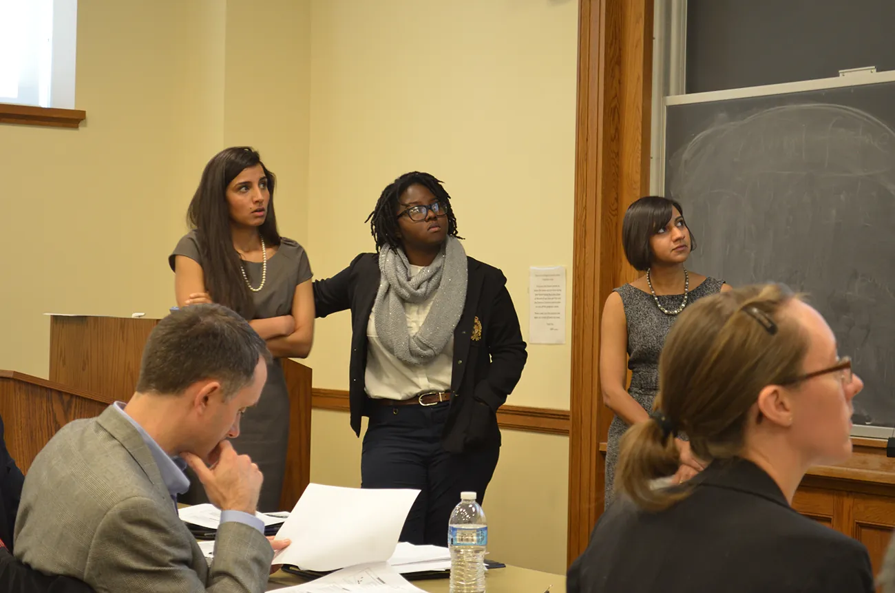 A photo shows a group of people attentively listening to a presentation in a meeting.
