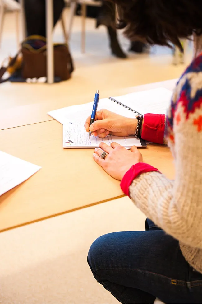A student takes down notes on a notebook inside a classroom.