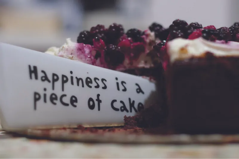 This image shows a knife cutting into a piece of cake. The knife says happiness is a piece of cake.
