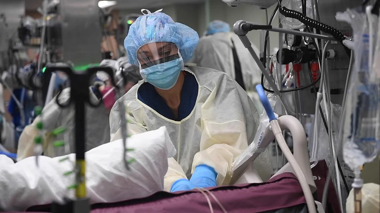 A color photograph shows medical professionals wearing protective clothing and equipment.