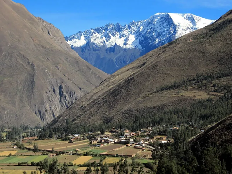 A valley between two very steep mountains. A third mountain is visible in the background, this one covered with snow.