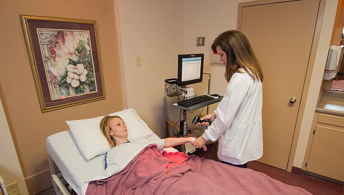 Photo of medical personnel scanning patient’s wristband with a hand held scanner in a hospital setting.