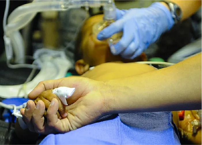 Photo of young child with breathing mask holding an adult’s hand.