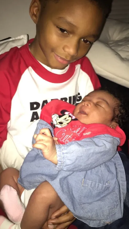 Photo of older sibling holding newborn.