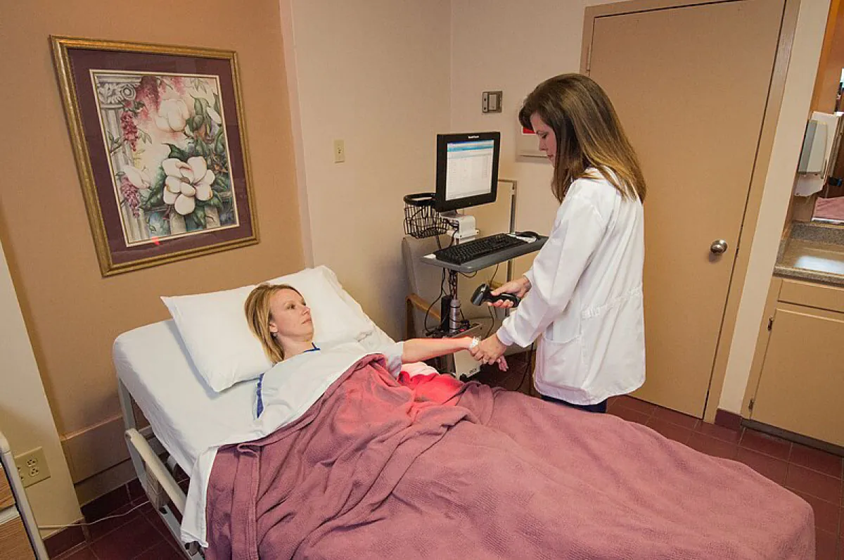 Image of patient in hospital bed and nurse scanning patient’s hospital bracelet.
