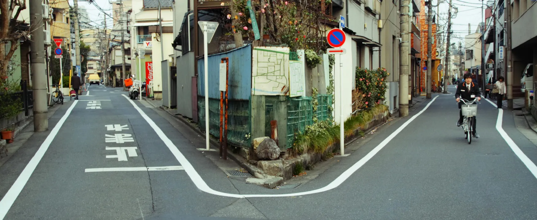 A photograph shows a street that branches into 2 paths; one going left, and one going right.