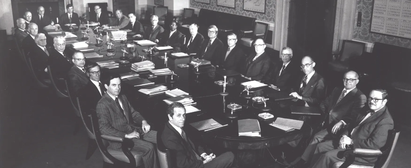 This image shows twenty-three White men and one Black man in suits sitting around a large boardroom-style table.