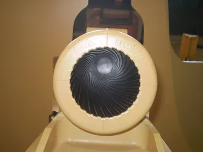 A close-up view looking down the rifled barrel of a large artillery piece or cannon, showcasing the distinct spiral grooves inside its muzzle.