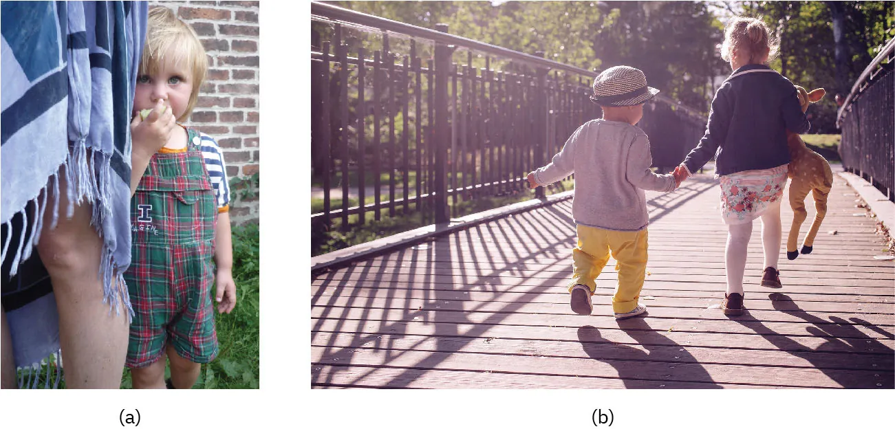 (a) Photo of young child standing close to an adult's legs. (b) Photo of two young children holding hands and running on a bridge.