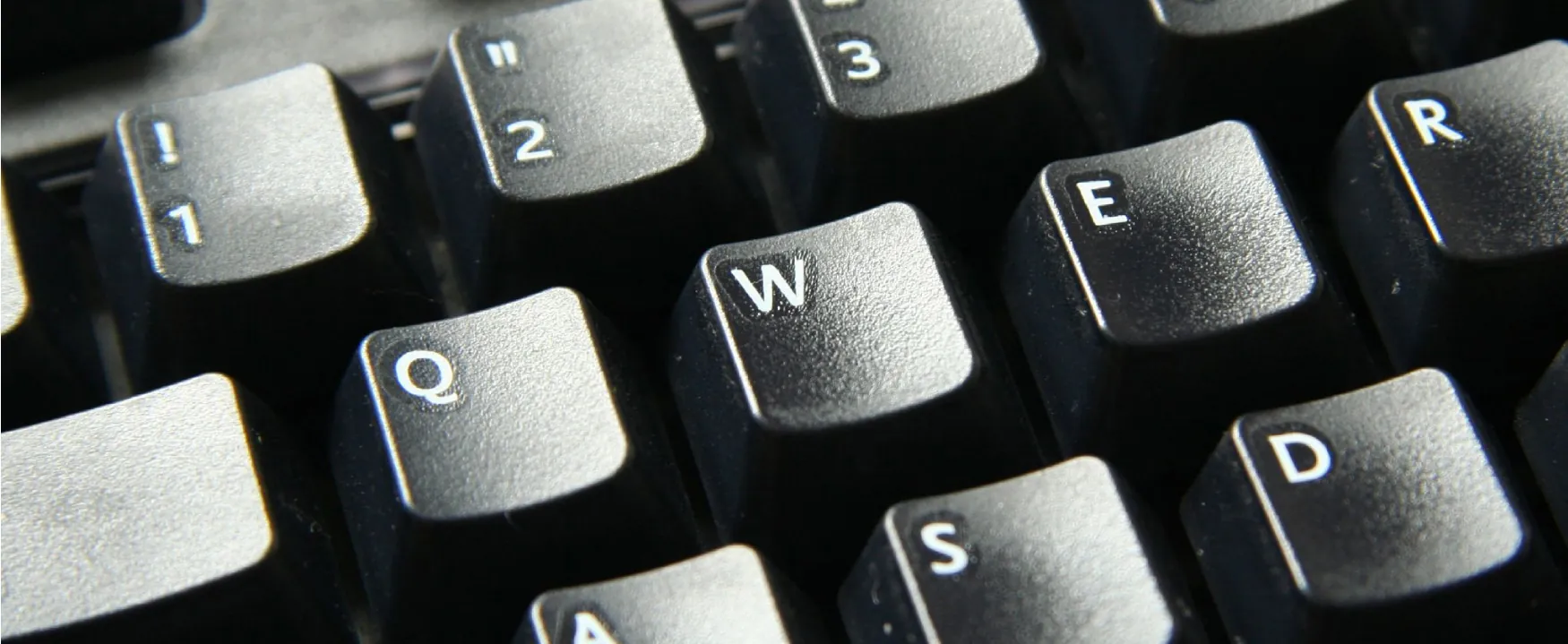 A detailed close-up of a computer keyboard, focusing on the QWERTY keys W, E, R and numerical keys 1, 2, 3. The textured surface and crisp white lettering are clearly visible, inviting interaction.