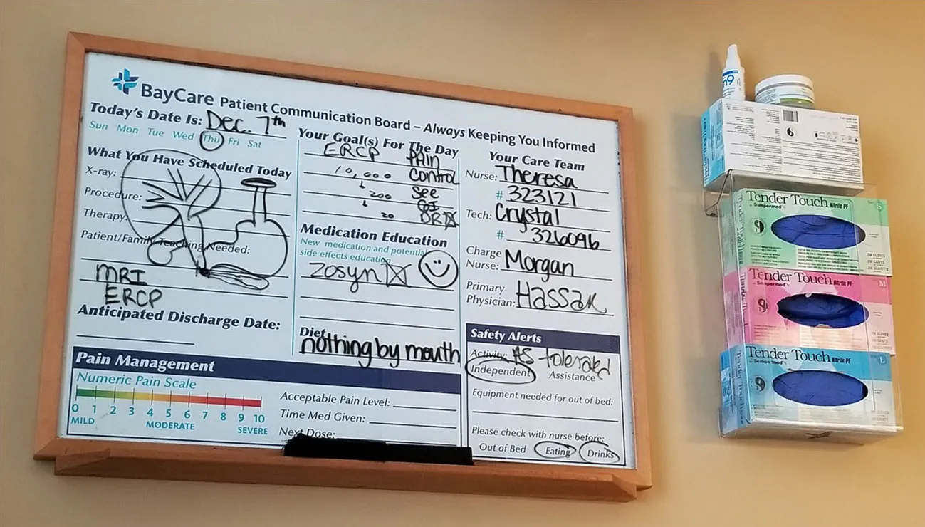 A photograph shows a communication board marked-up with notes on a patient such as medication and food restrictions.