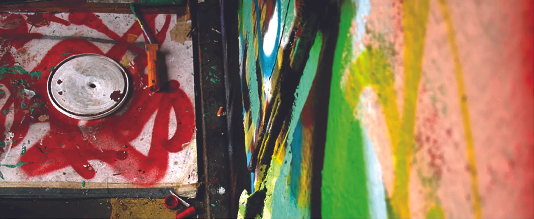 A photo of a messy paint lid and canvas.