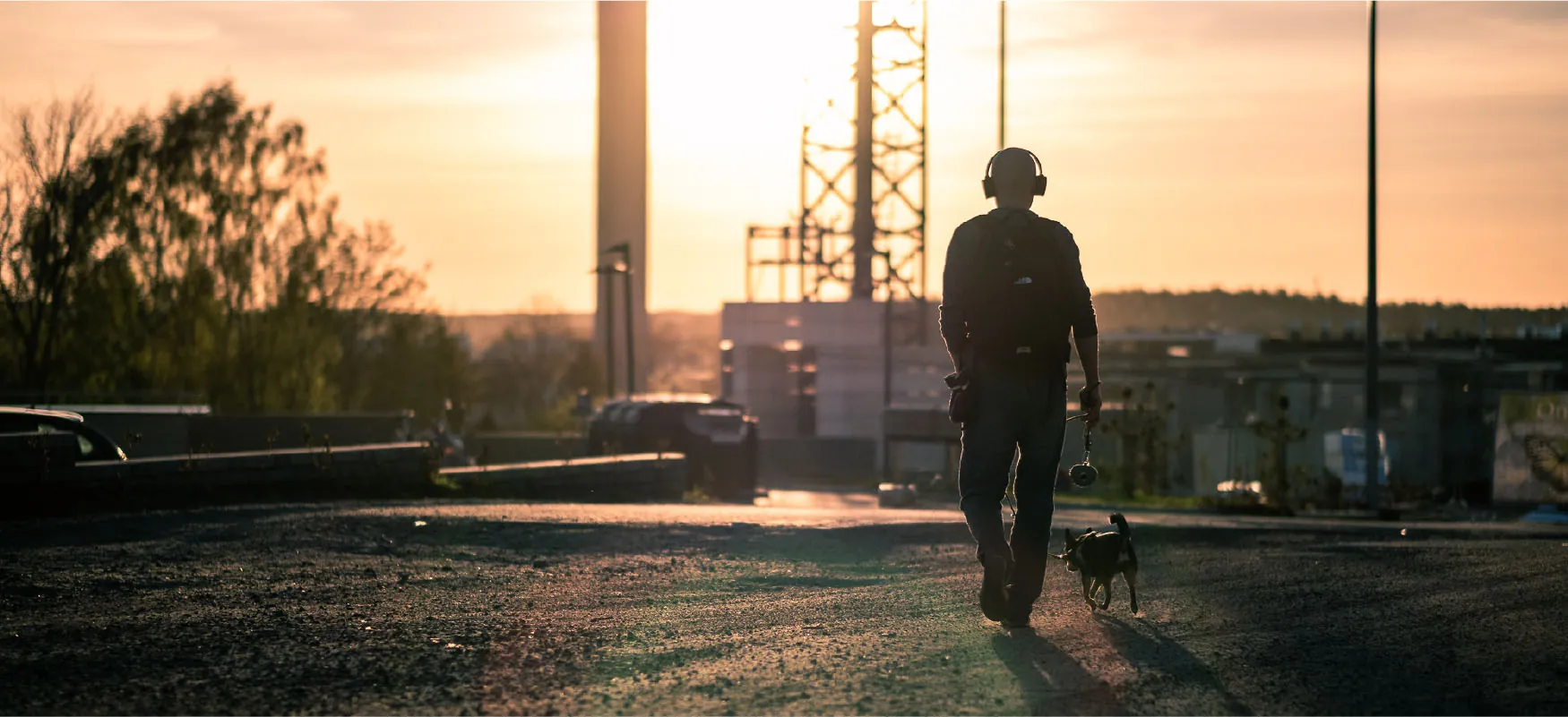A person wearing headphones walks a dog.