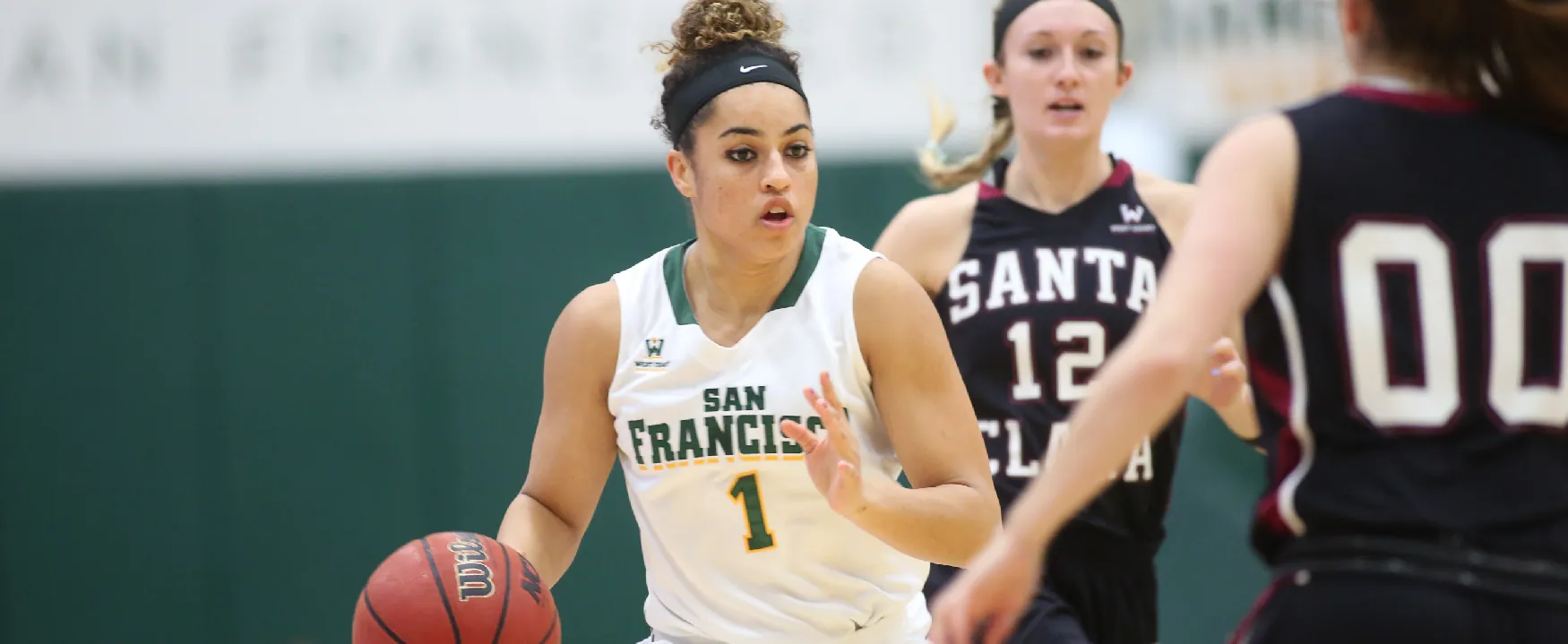 A photo shows three female basketball players playing basketball.