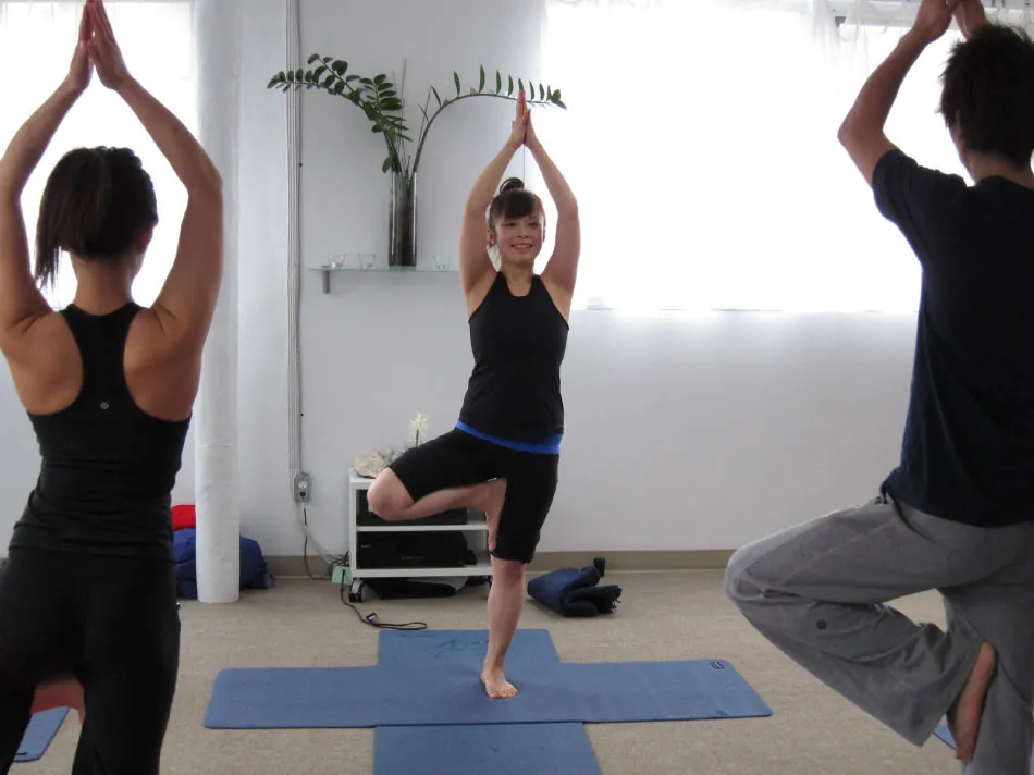 Photo of three individuals practicing Tai Chi on mats.