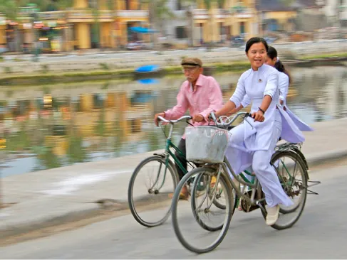 La imagen muestra a tres personas montando en bicicleta junto a un canal.