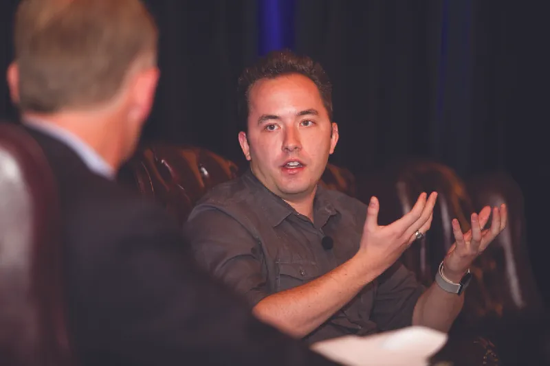 Photo of Andrew Houston talking to another person.