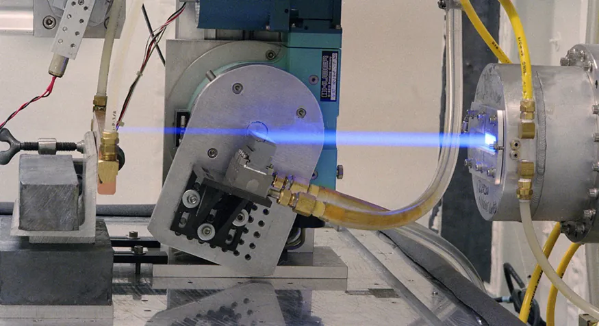 The image shows a ray of blue light being emitted from a small slit in a cylindrical source.