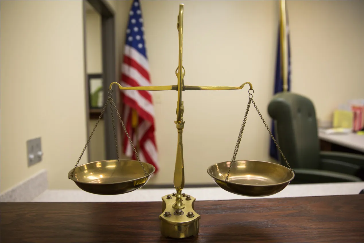 A brass scale on a desk with a flag in the background