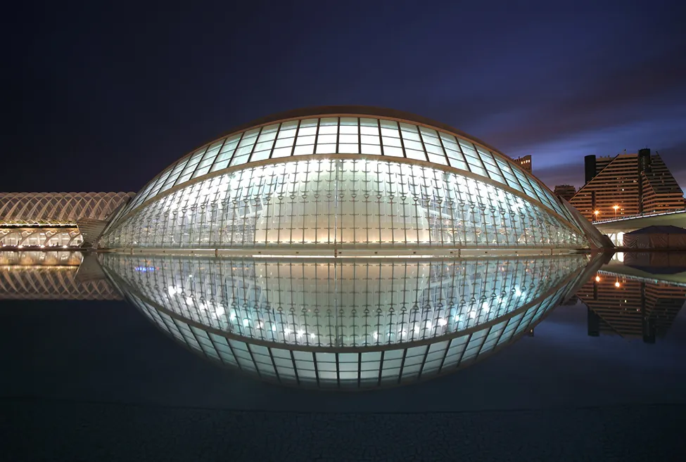 A photo of a glass ovoid dome reflecting in the water to make something like a football shape.