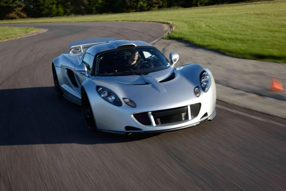 Foto de un deportivo Hennessey Venom GT circulando a toda velocidad por una carretera sinuosa.