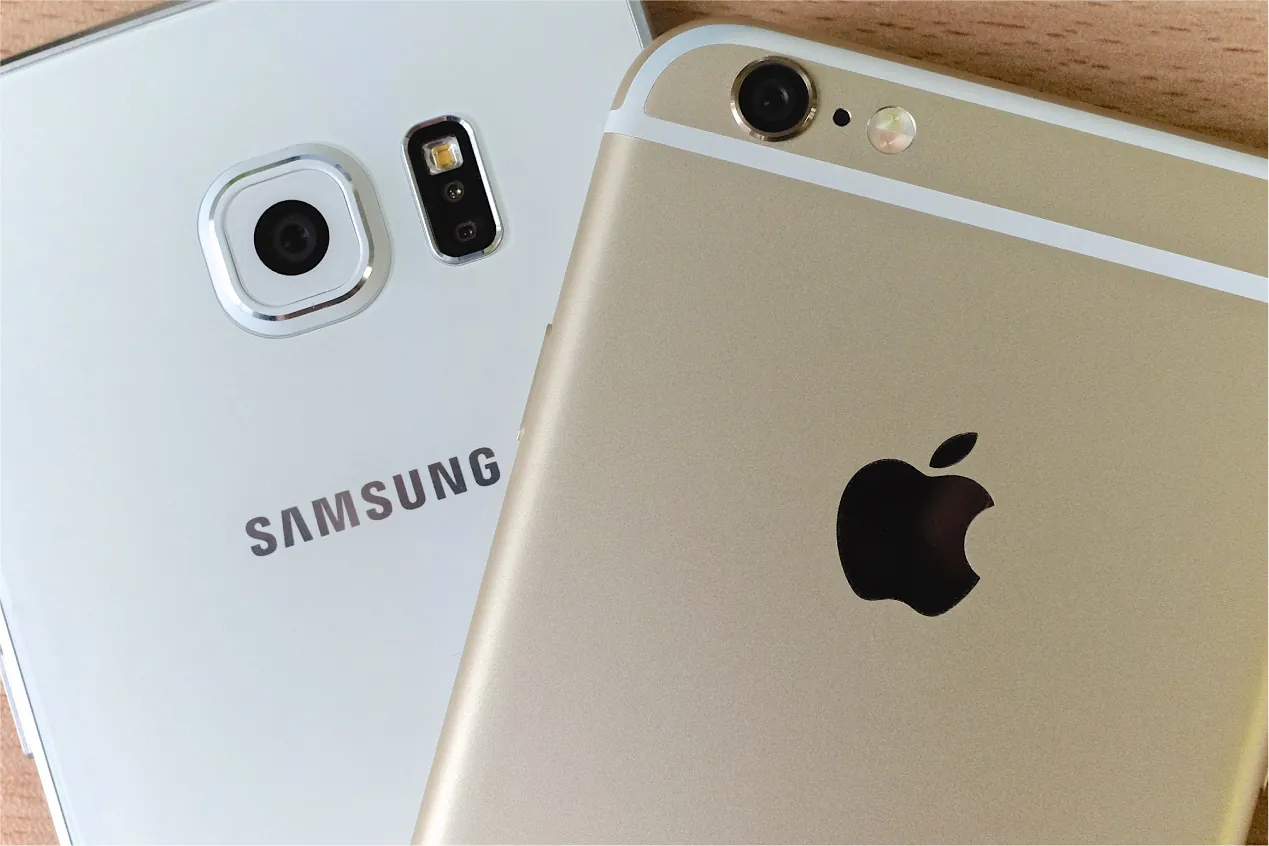 Two cell phones, one with an Apple logo and one with a Samsung logo.