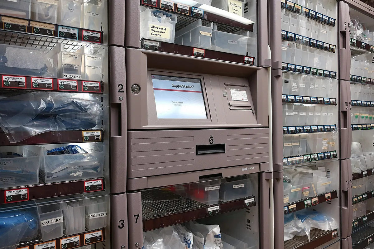 Photo of an automated medication dispensing system with a computer screen in the middle and many labeled drawers filled with medications.