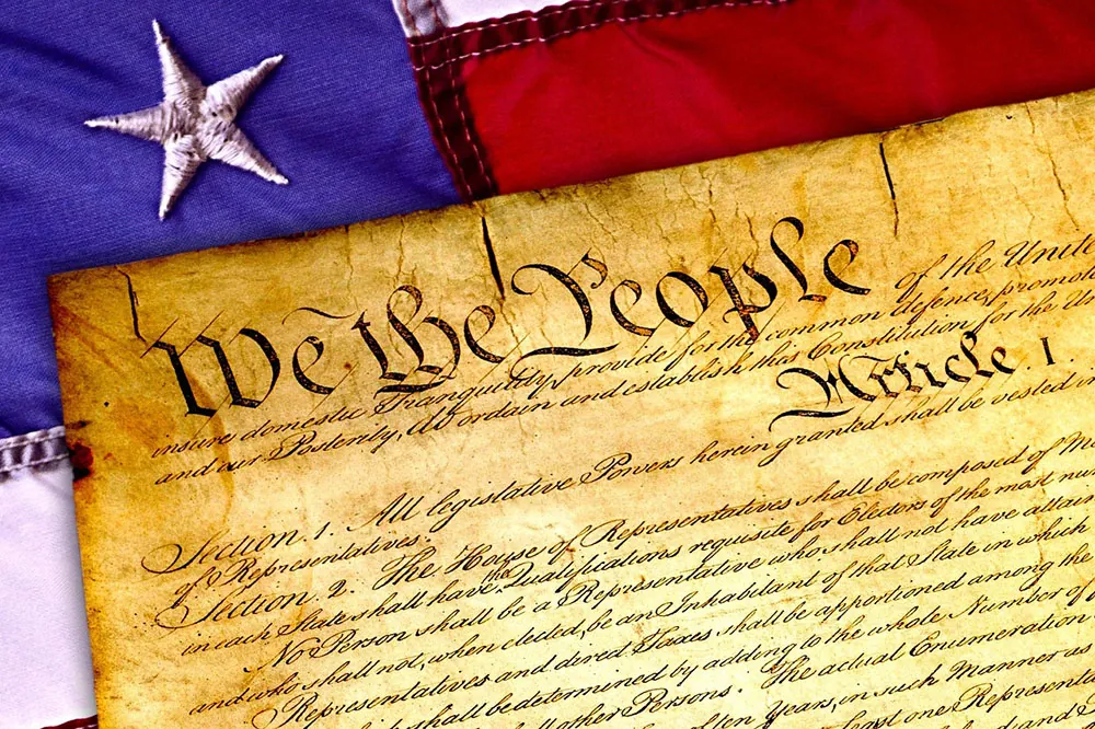 An image of the U.S. Constitution on top of an old American flag.