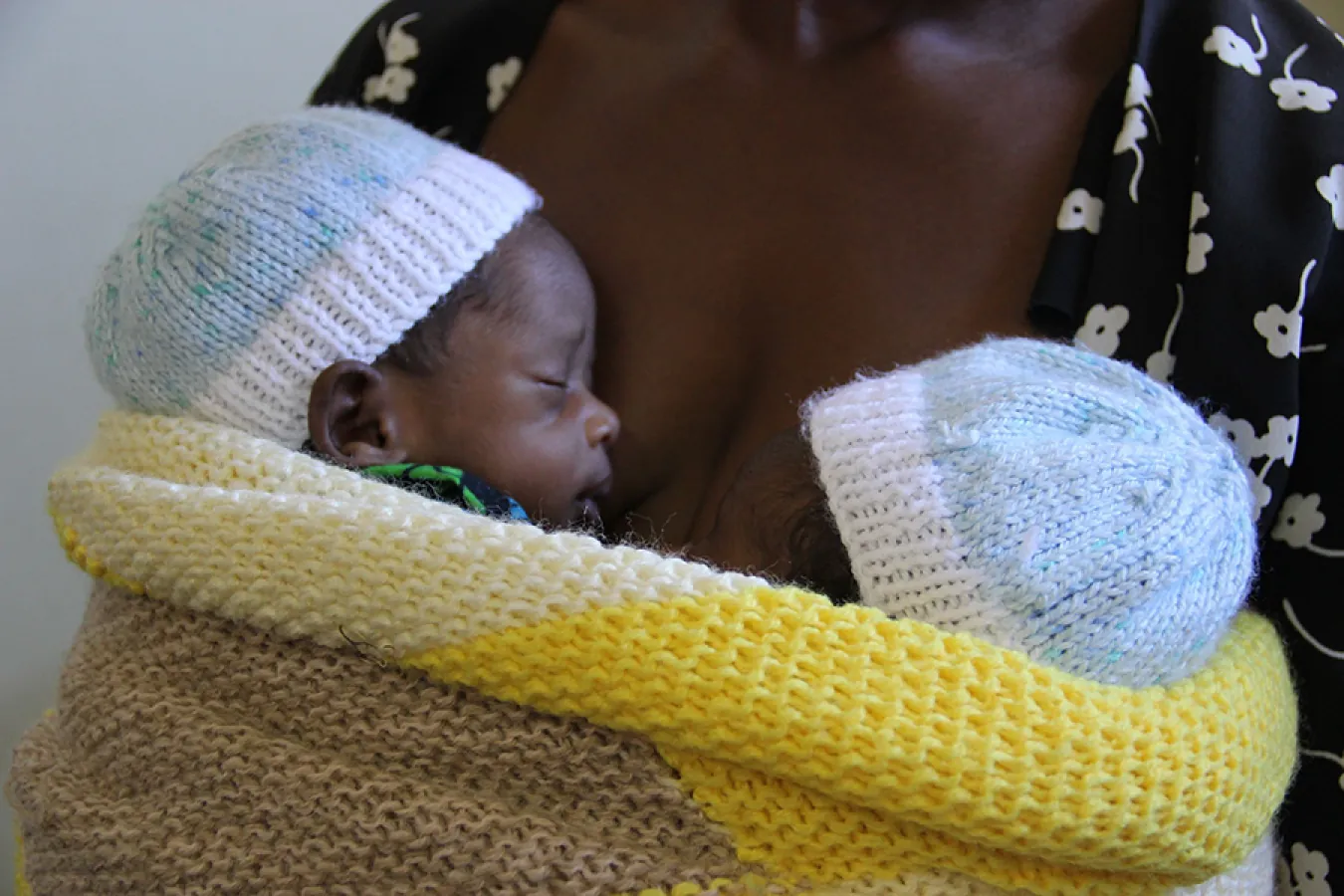 Mother holding two infants on her bare chest.