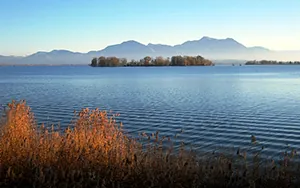 Waves ripple across a lake by the mountains.